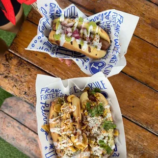 two hotdogs with toppings and a glass of wine