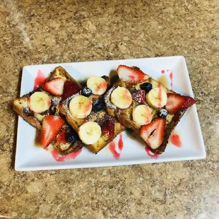 a plate of french toast with strawberries and bananas