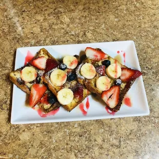 a plate of french toast with strawberries and bananas