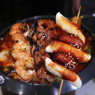 a closeup of a skewer of shrimp, sausage, and shrimp