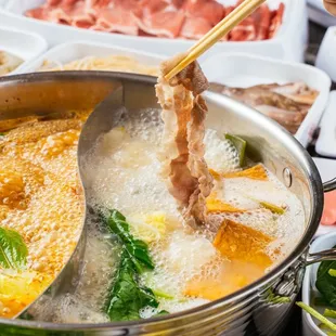 a pot of soup with chopsticks