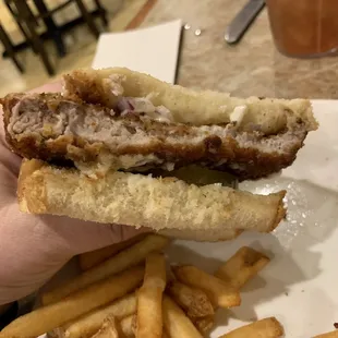 a hand holding a sandwich and french fries
