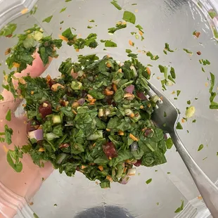 a hand holding a bowl of salad