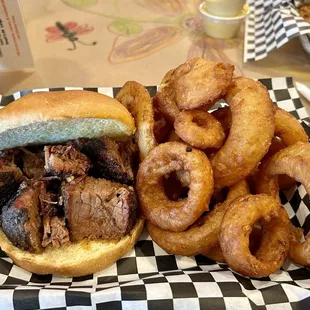 The burnt end sandwich with a side of onion rings.