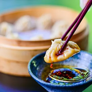 a person dipping a dumpling into a bowl