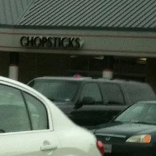 a white car in front of a chopsticks store