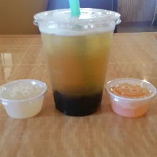 a plastic cup with a straw and two small bowls of sauce