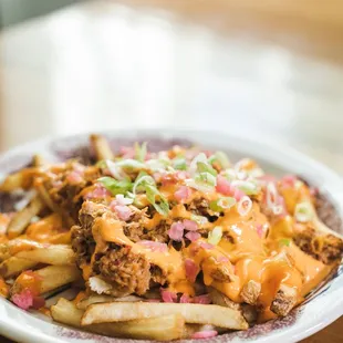 a plate of fries with cheese and onions