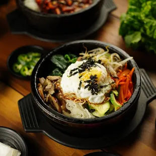 Bibimbap options: Meat, Kimchi, Spicy Squid, and Vegetarian. Pictured: Spicy Squid Bibimbap (back) and Vegetarian Bibimbap (front).
