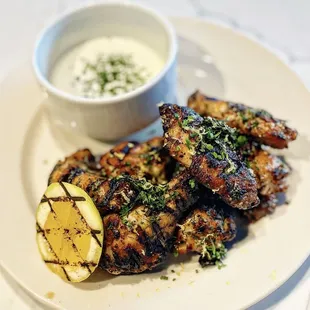 a plate of grilled chicken with a side of yogurt