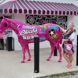 a woman standing next to a pink horse