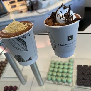 DRINKING CHOCOLATE- one with Passion Fruit, whipped cream and white chocolate shavings and the other with marshmallow topping.