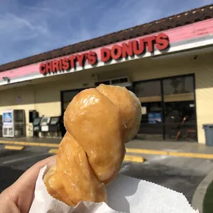 a hand holding a glazed donut
