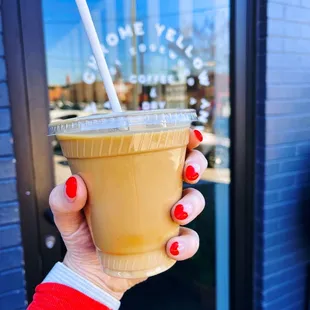 a hand holding a cup of iced coffee