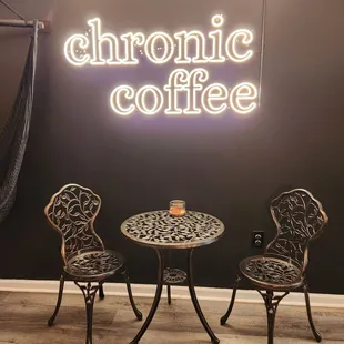 two chairs and a table in front of a neon sign