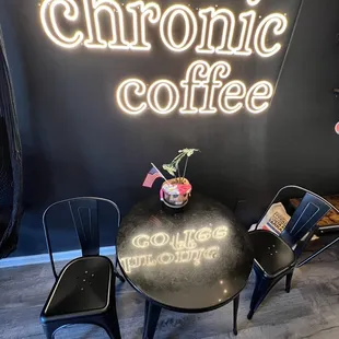 a table and chairs in front of a neon sign