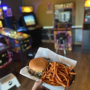 a hand holding a hamburger and fries