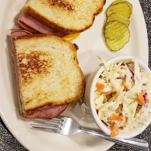 a plate with a sandwich, coleslaw and pickle