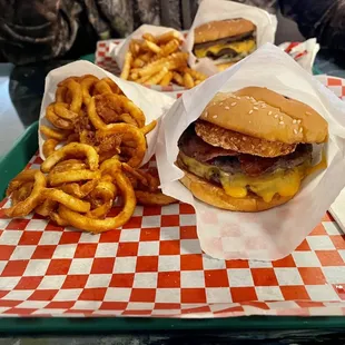 In front: Double bison burger w/bacon, cheddar, &amp; a hash brown + seasoned curlies. In back: Hickory Bbq bison burger w/crinkles