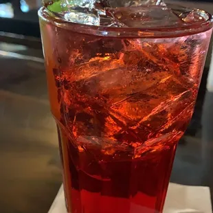 a red drink with ice and a green straw