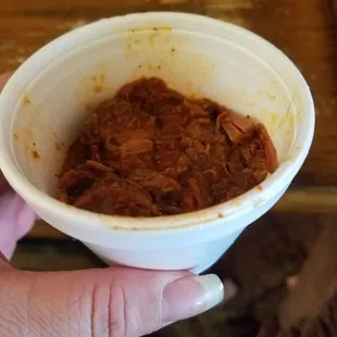 ows a hand holding a bowl of food