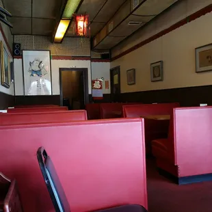 the interior of a restaurant with red booths