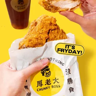 two hands holding a bag of fried chicken