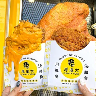 two hands holding up two bags of fried chicken