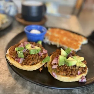 Sopes Desayuno w/chorizo, onion, cilantro, avocado, with a tangy green sauce on a handmade sope and a side of delicate hash browns.