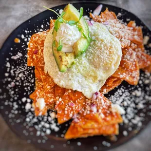 Chilaquiles- 2 eggs, avocado, sour cream, cilantro, onion, and red sauce on a bed of tortilla chips.