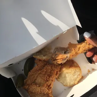 a hand holding a piece of fried chicken