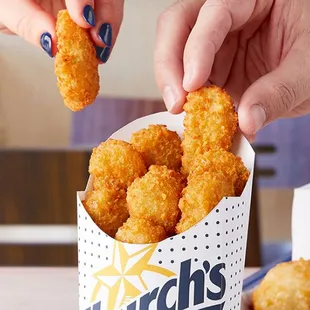 a hand picking up a fried chicken nuggies