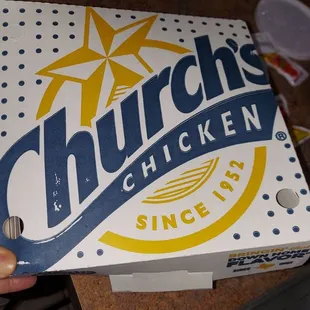 a hand holding a box of chicken