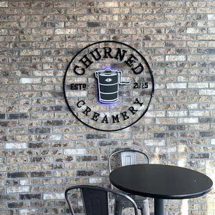 a table and chairs in front of a brick wall