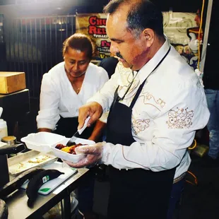 two men preparing food in a kitchen