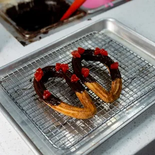 two chocolate covered donuts on a cooling rack