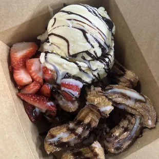 Churro bites with vanilla ice cream + strawberries  chocolate drizzle.