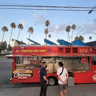 two people standing in front of a food truck