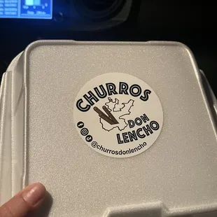 a hand holding a styrofoam container