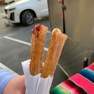 a person holding two churros