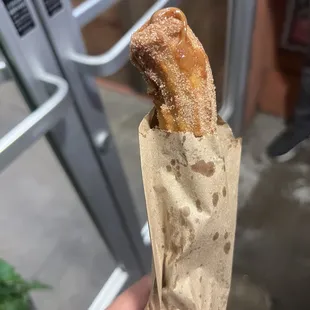 a hand holding a bag of churros