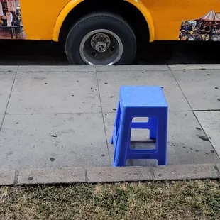 a blue stool on the sidewalk