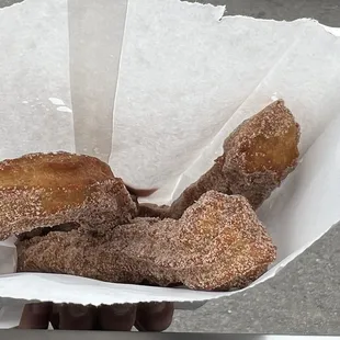 a person holding a paper basket of churros