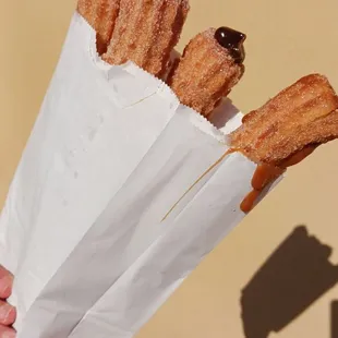 a person holding a bag of churros