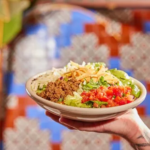 It's a taco...but a salad! Fresh salad mix with tortilla strips, cheese, gua­camole, tomatoes &amp; your choice of protein!