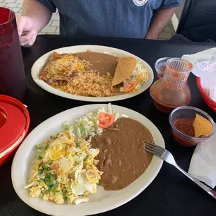 a man sitting at a table with two plates of mexican food