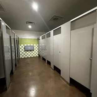 women&apos;s restroom has a lot of stalls and a baby changing station