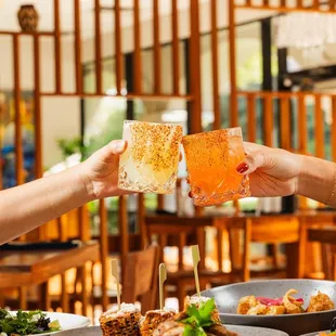 two people toasting over plates of food