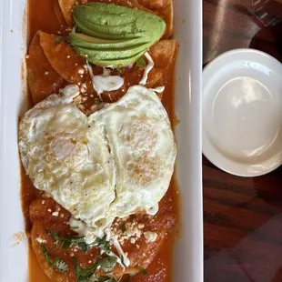 Eggs over tortillas with onion, avocado, and a light, fresh red sauce.
