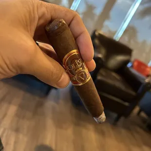 a hand holding a cigar in a living room
